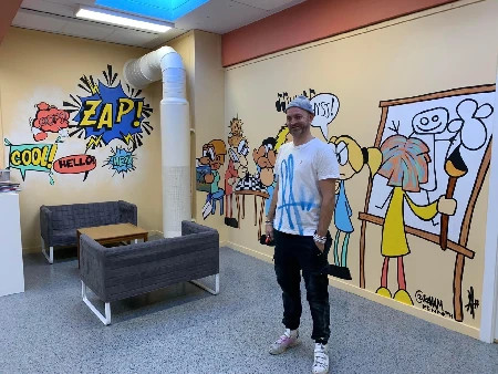 Colorful comic-style wall mural by KAAAM in the common room at Drøbak School